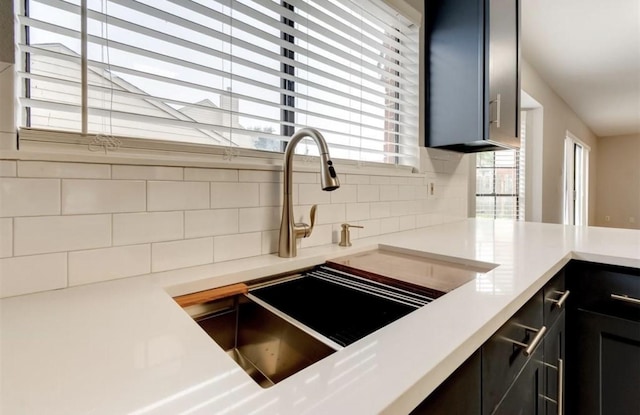 kitchen with tasteful backsplash, a sink, light countertops, a peninsula, and dark cabinets