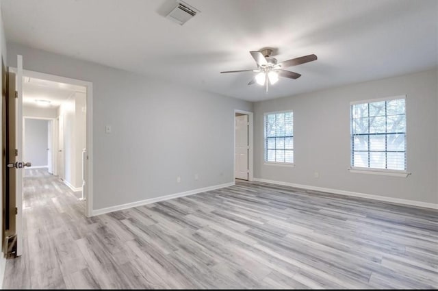 empty room featuring light wood-style floors, baseboards, ceiling fan, and visible vents