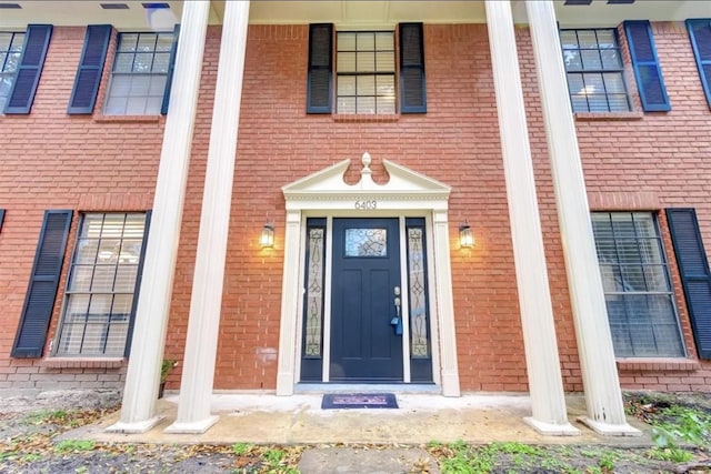 doorway to property featuring covered porch and brick siding