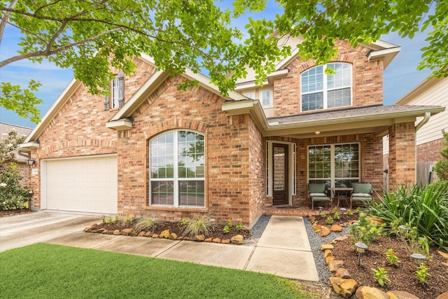 traditional-style house featuring covered porch, brick siding, an attached garage, and driveway