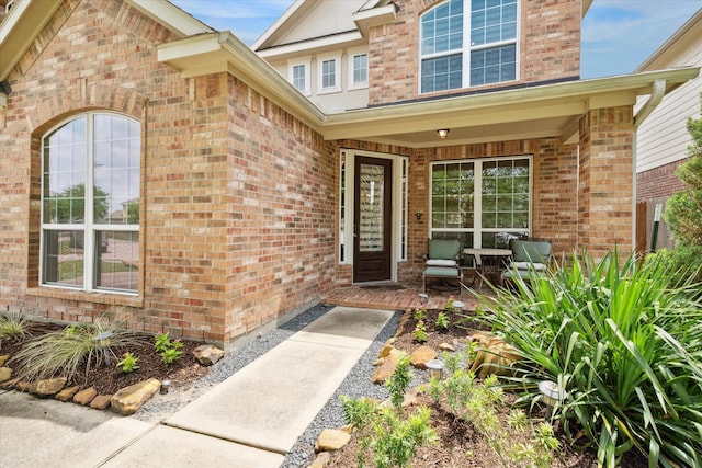 entrance to property with covered porch and brick siding