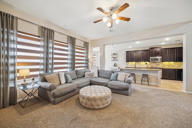 living area with ceiling fan and light carpet