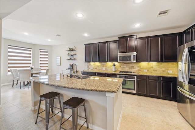 kitchen featuring a sink, decorative backsplash, appliances with stainless steel finishes, and light tile patterned flooring