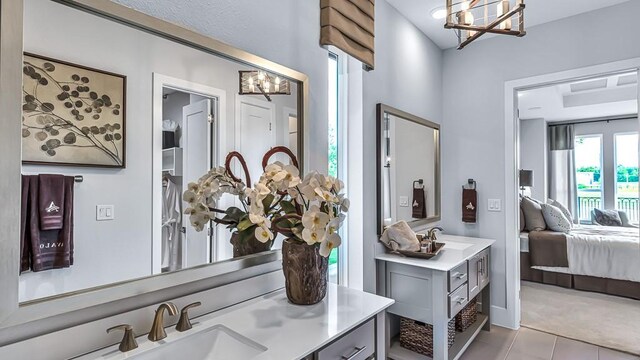 interior space featuring connected bathroom, an inviting chandelier, tile patterned flooring, and vanity