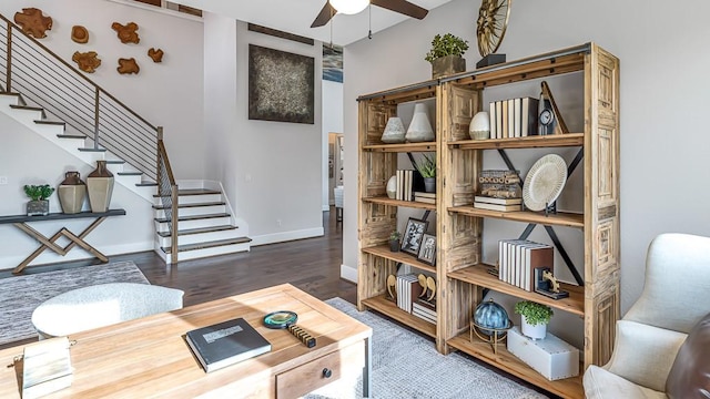 living area featuring stairway, baseboards, ceiling fan, and wood finished floors
