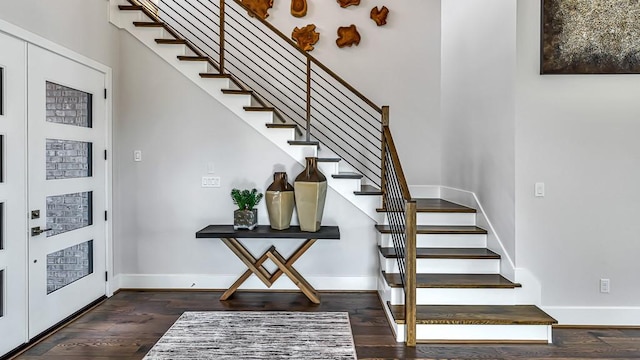 foyer featuring baseboards, wood finished floors, and stairway
