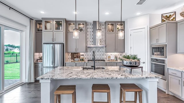 kitchen with visible vents, wall chimney range hood, gray cabinetry, and stainless steel appliances