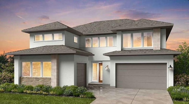 prairie-style house featuring an attached garage, concrete driveway, and stucco siding