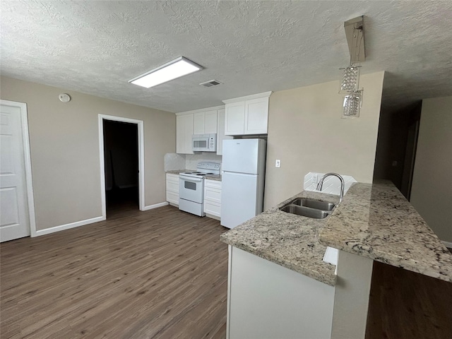 105 Will St, Willis, TX 77378 - kitchen with visible vents, white appliances, dark wood-style floors, white cabinetry, and a sink