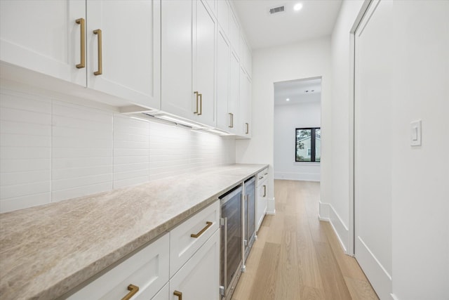 1550 Gardenia Dr, Houston, TX 77018 - kitchen featuring white cabinets, beverage cooler, tasteful backsplash, light wood finished floors, and recessed lighting