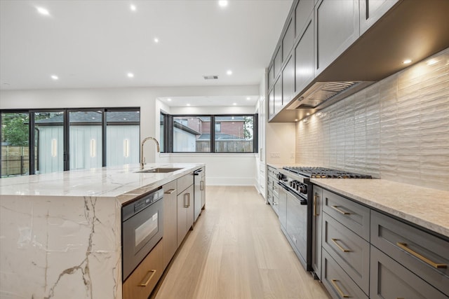 1550 Gardenia Dr, Houston, TX 77018 - kitchen featuring stainless steel range, a sink, light wood-style floors, a center island with sink, and decorative backsplash