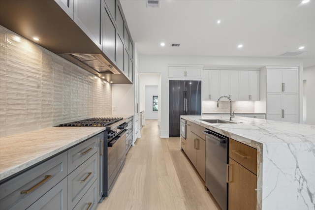 1550 Gardenia Dr, Houston, TX 77018 - kitchen featuring stainless steel appliances, a sink, tasteful backsplash, light wood finished floors, and light stone counters