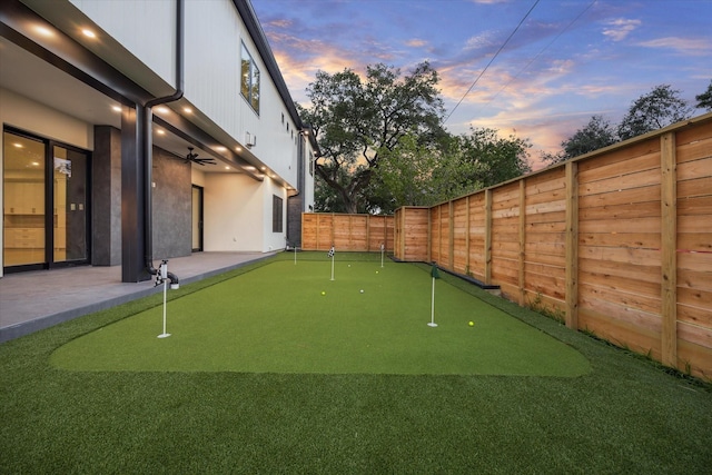 1550 Gardenia Dr, Houston, TX 77018 - yard at dusk featuring a putting green, a fenced backyard, a patio area, and a ceiling fan