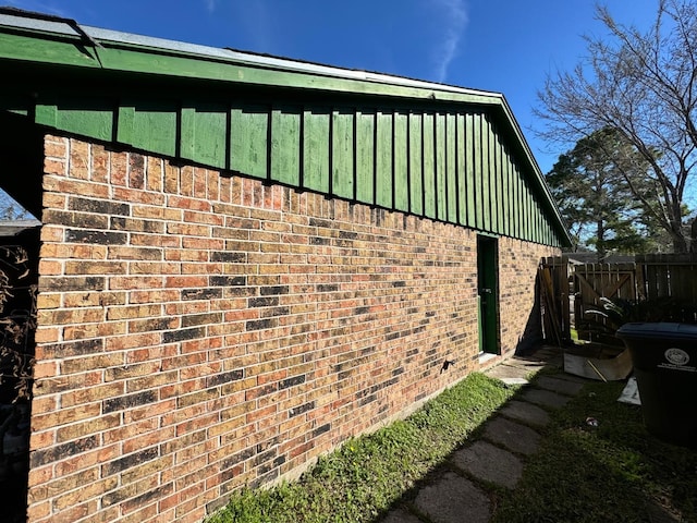 view of side of property featuring board and batten siding, brick siding, and fence