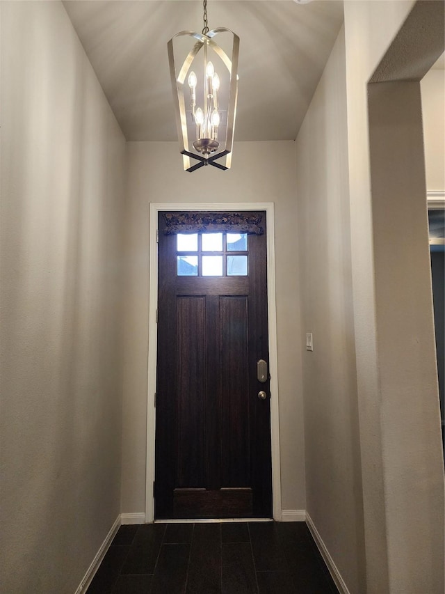 entryway with baseboards and a chandelier