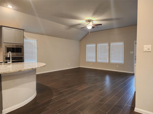 unfurnished living room with baseboards, ceiling fan, a sink, and dark wood-type flooring