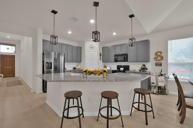 kitchen featuring decorative backsplash, gray cabinets, visible vents, light stone countertops, and black appliances