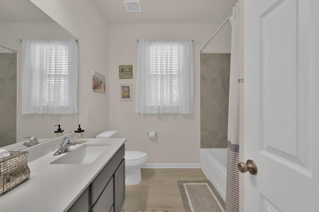 bathroom featuring visible vents, shower / tub combo, baseboards, vanity, and toilet