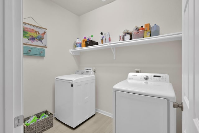 clothes washing area with separate washer and dryer, laundry area, and light wood-style flooring