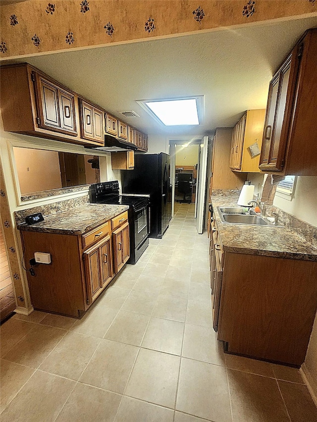 kitchen featuring a textured ceiling, visible vents, black electric range oven, a sink, and light tile patterned floors