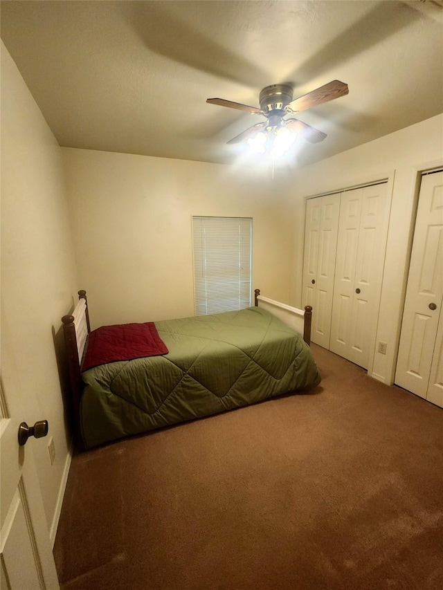bedroom featuring two closets, a ceiling fan, baseboards, and carpet