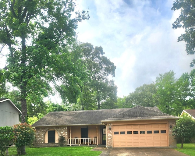 ranch-style house featuring an attached garage, a front lawn, brick siding, covered porch, and driveway
