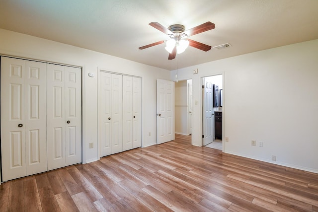 3306 Sycamore Springs Dr, Houston, TX 77339 - unfurnished bedroom featuring two closets, light wood-type flooring, baseboards, ensuite bath, and ceiling fan