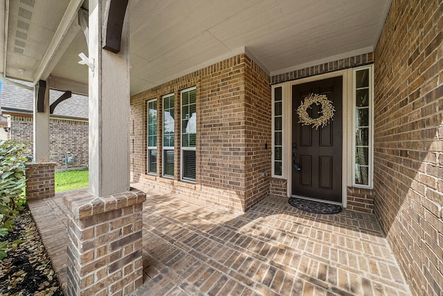 entrance to property with covered porch and brick siding