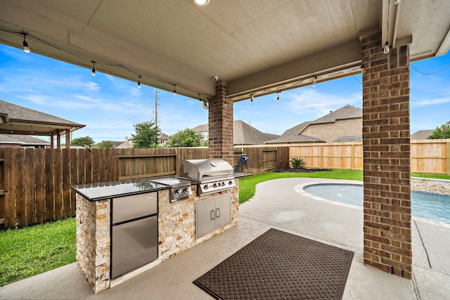 view of patio with grilling area, an outdoor kitchen, a fenced in pool, and a fenced backyard