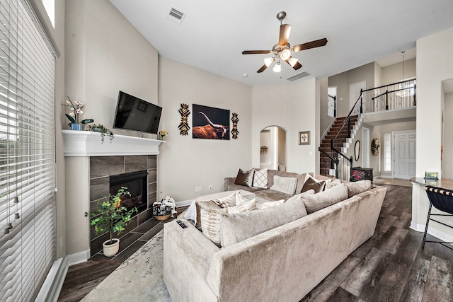 living area with dark wood-style flooring, a high ceiling, plenty of natural light, and stairway