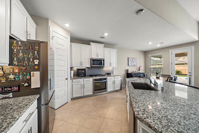 kitchen featuring visible vents, white cabinetry, a sink, appliances with stainless steel finishes, and backsplash