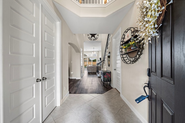 entryway featuring baseboards, arched walkways, and light tile patterned floors