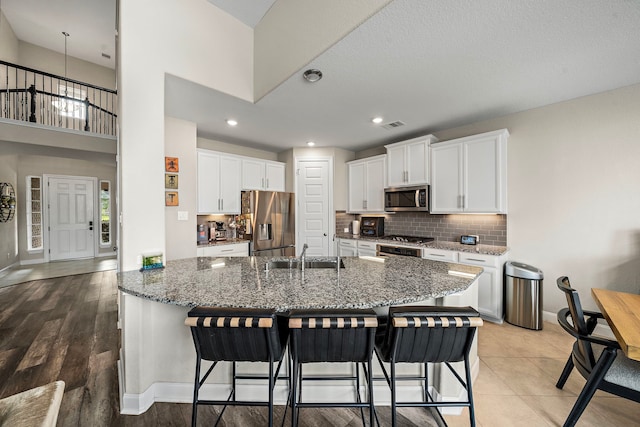 kitchen with white cabinets, stainless steel appliances, a breakfast bar, and a sink
