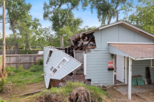 view of side of property featuring fence and roof with shingles
