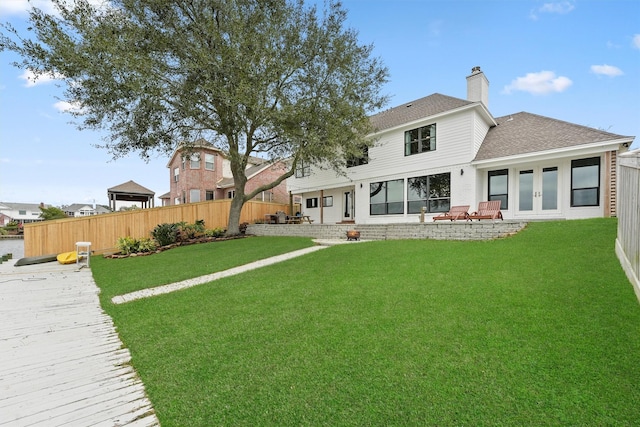 10 Quintana Pl, Galveston, TX 77554 - rear view of house featuring fence, a shingled roof, french doors, a chimney, and a lawn