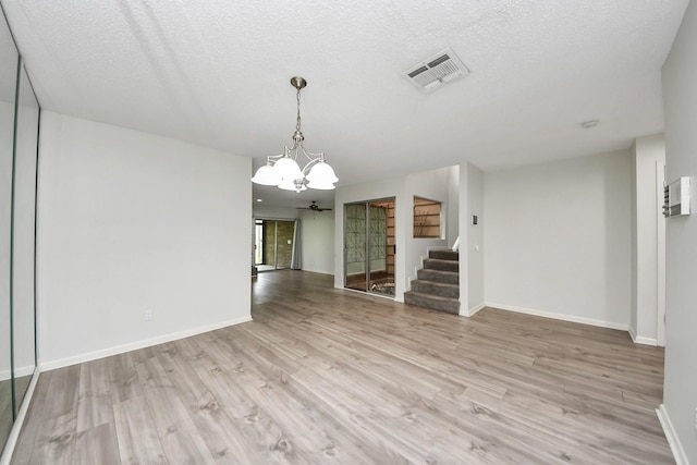 unfurnished dining area with stairway, visible vents, light wood-style flooring, and a chandelier