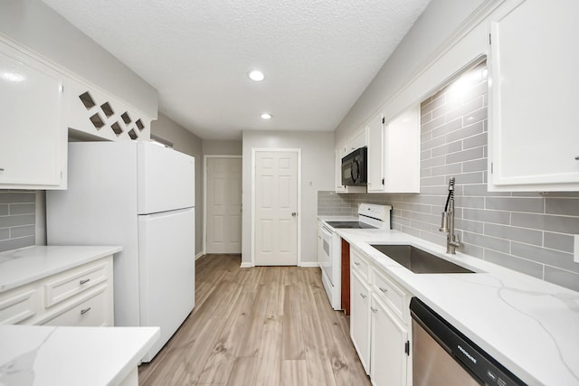 kitchen with white appliances, white cabinetry, a sink, and backsplash