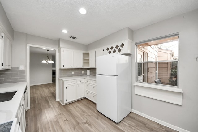 kitchen featuring light wood-type flooring, freestanding refrigerator, and white cabinetry