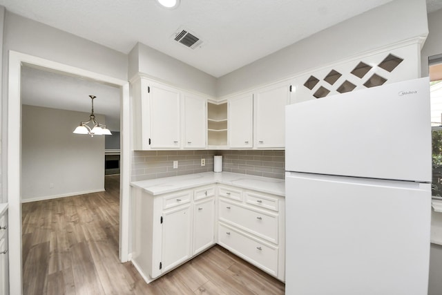 kitchen featuring an inviting chandelier, freestanding refrigerator, open shelves, visible vents, and white cabinetry