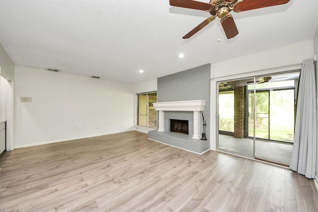 unfurnished living room featuring light wood finished floors, a brick fireplace, recessed lighting, and visible vents