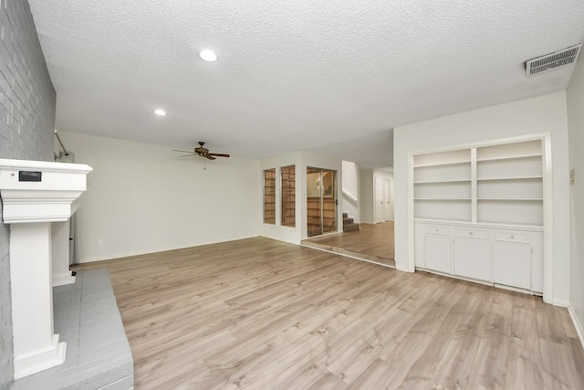 unfurnished living room with visible vents, stairs, ceiling fan, a textured ceiling, and light wood finished floors