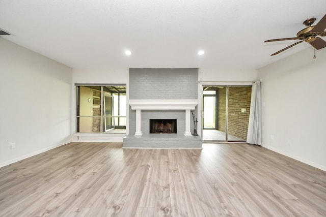 unfurnished living room featuring a ceiling fan, baseboards, wood finished floors, and a fireplace