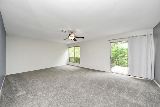 empty room with carpet flooring, a ceiling fan, baseboards, and visible vents