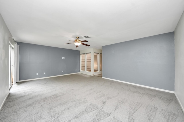 carpeted spare room with baseboards, a ceiling fan, and visible vents