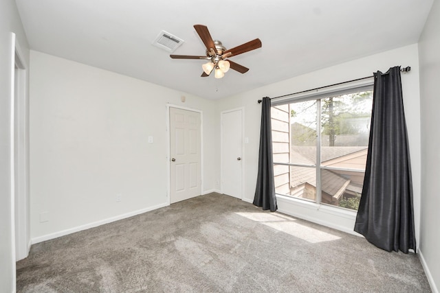 carpeted spare room featuring baseboards, ceiling fan, and visible vents