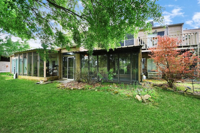 back of house featuring a lawn and a sunroom