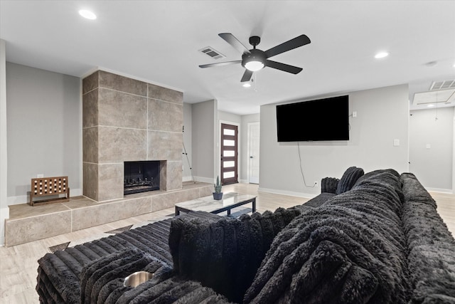 living area featuring a ceiling fan, recessed lighting, wood finished floors, baseboards, and a tiled fireplace