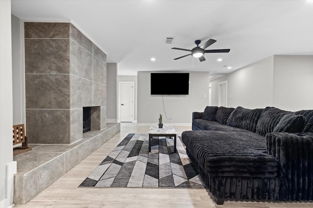 living room featuring a ceiling fan, light wood-style floors, recessed lighting, a fireplace, and baseboards