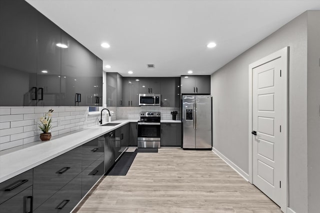 kitchen featuring appliances with stainless steel finishes, modern cabinets, backsplash, a sink, and recessed lighting