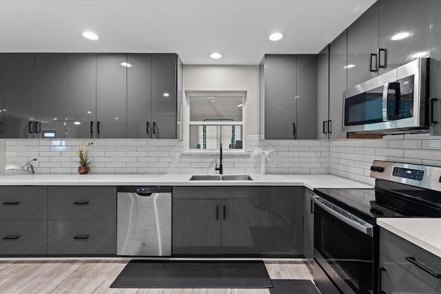 kitchen with stainless steel appliances, a sink, gray cabinets, and modern cabinets